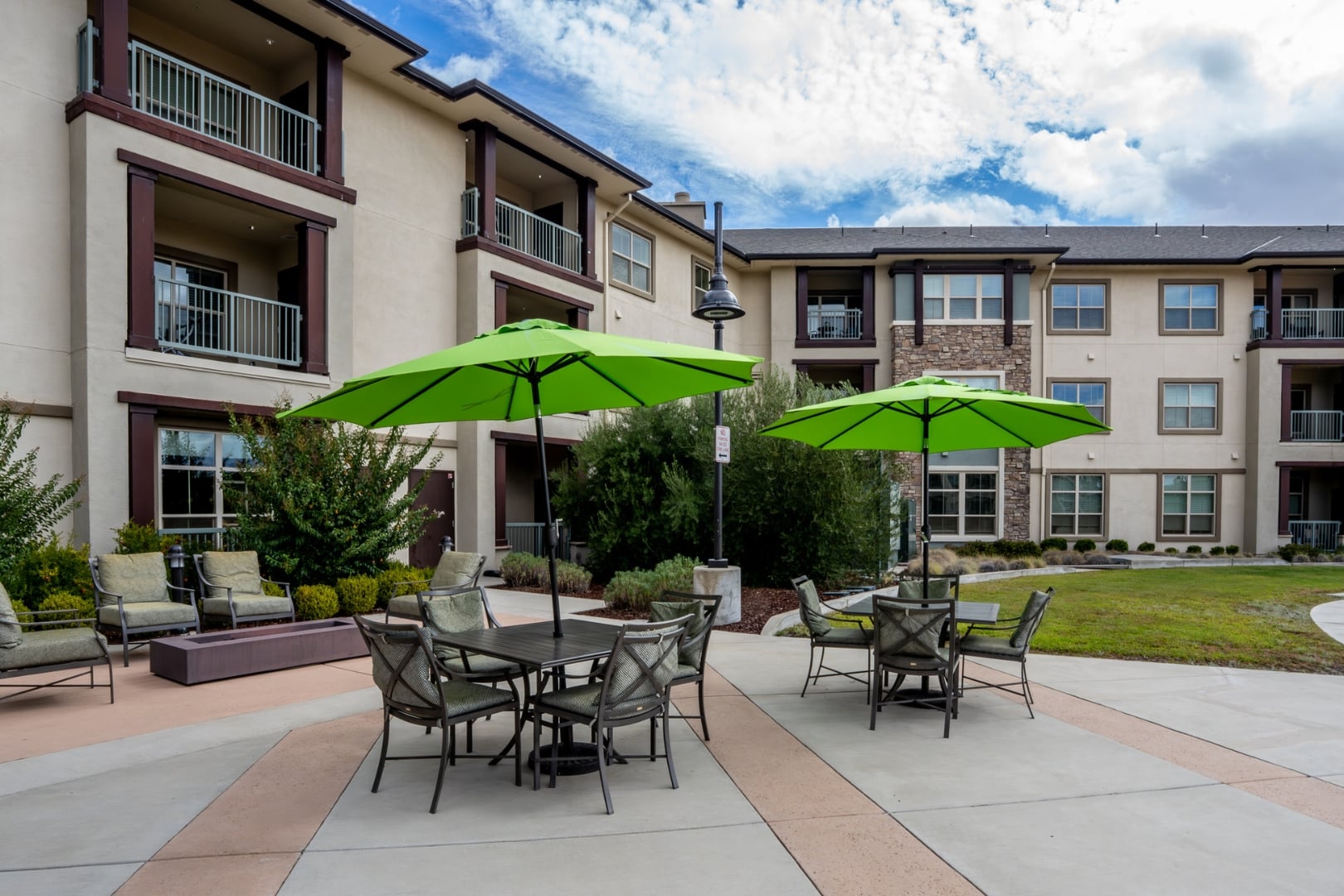 Outdoor Patio Seating with Green Umbrellas at Independent Living Facility