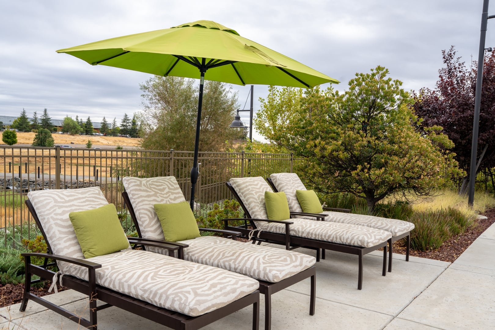 Poolside Lounge Chairs under Green Umbrella at Independent Living Facility